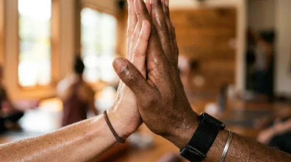 Close-up detail shot of two hands meeting in an energetic high-five, fingers extended and palms connecting with dynamic energy, beads of perspiration visible on skin