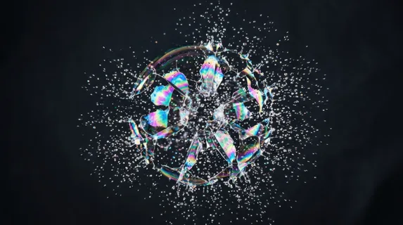 Macro shot of a soap bubble at the precise moment of rupture, the iridescent membrane fragmenting into thousands of microscopic droplets fanning outward in a perfect