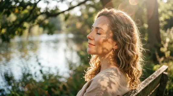 Side profile of a woman with eyes closed, experiencing the warmth of direct sunlight on her face, light rays creating lens flares around loose curls and fine hair details