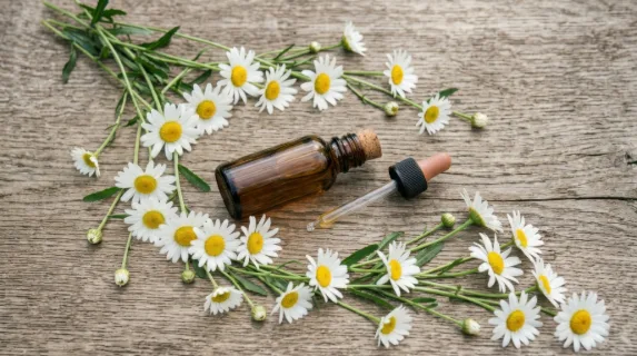 an overhead view of the amber serum bottle and oxeye daisies, emphasizing the arrangement and interplay of the elements with dynamic angles that create a sense of