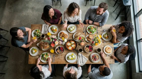 an overhead perspective of the brunch spread beautifully laid out on the table, featuring the food stylist in the background, joyfully interacting with guests. the