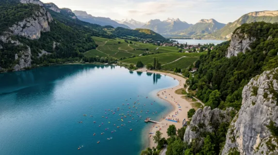 a distinct overhead angle capturing the tranquil mountain lake and colorful tow floats, framed by rocky gray cliffs and sandy beige lakeshore that seamlessly blends into