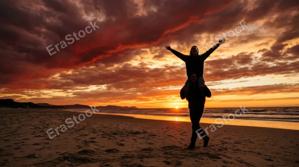 Silhouetted figure carrying another on shoulders against brilliant sunset horizon, arms stretched wide in celebration, dramatic clouds painted in deep crimsons and golds,