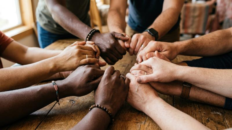 Diverse hands joining together to symbolize unity and collaboration, close-up composition, varied skin tones, soft natural light and a strong inspiring teamwork mood, ultra-realistic, no logos.