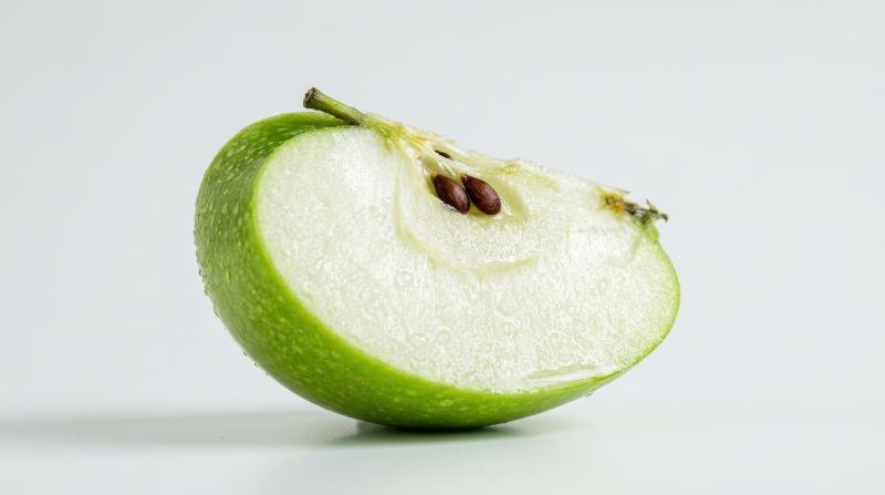 A juicy green apple wedge isolated on a clean backdrop, visible seeds, crisp flesh and tiny water droplets, fresh healthy-food styling, ultra-realistic, no logos.