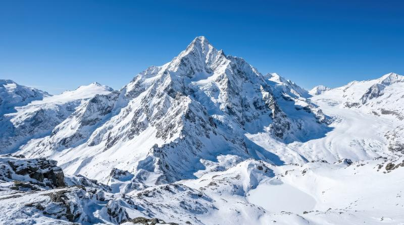 A snow-covered mountain peak beneath a clear sky, icy ridges, crisp alpine air and majestic winter stillness, ultra-realistic, no logos.