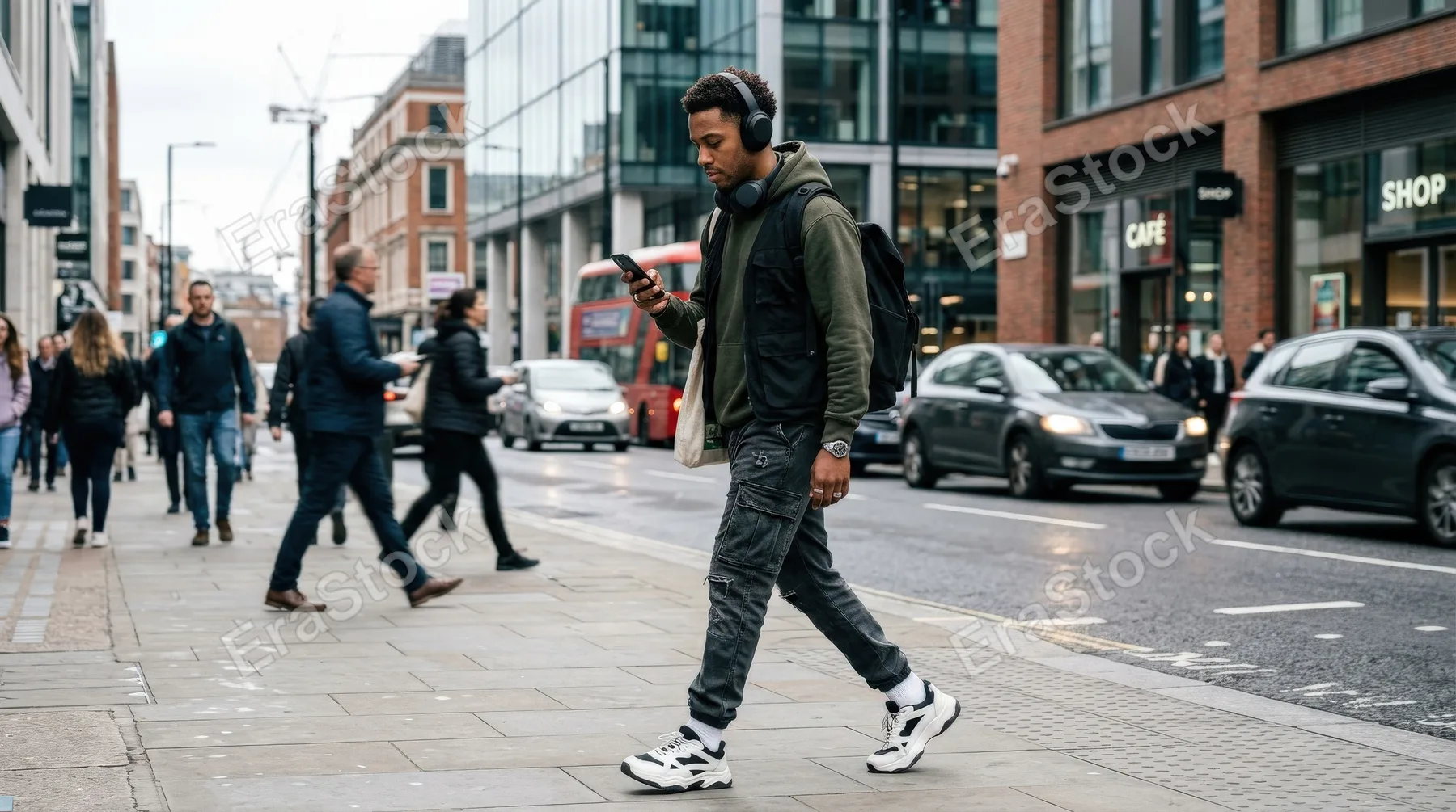 An urban man with headphones checking his smartphone outdoors, streetwear styling, modern city backdrop, candid motion, cool everyday rhythm, ultra-realistic, no logos.