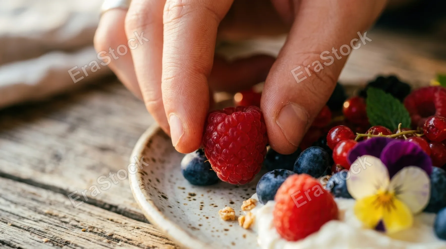a close-up detail shot of the colorful food items being arranged on a rustic wooden table by a young white male. this intimate composition highlights the textures and