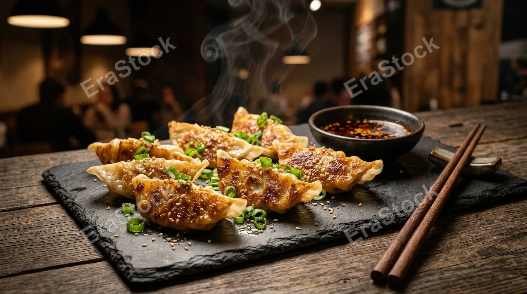 Crispy pan-fried dumplings garnished with fresh green onions, served with soy sauce and chopsticks on a dark slate plate, golden crust, appetizing steam and moody restaurant light, ultra-realistic, no