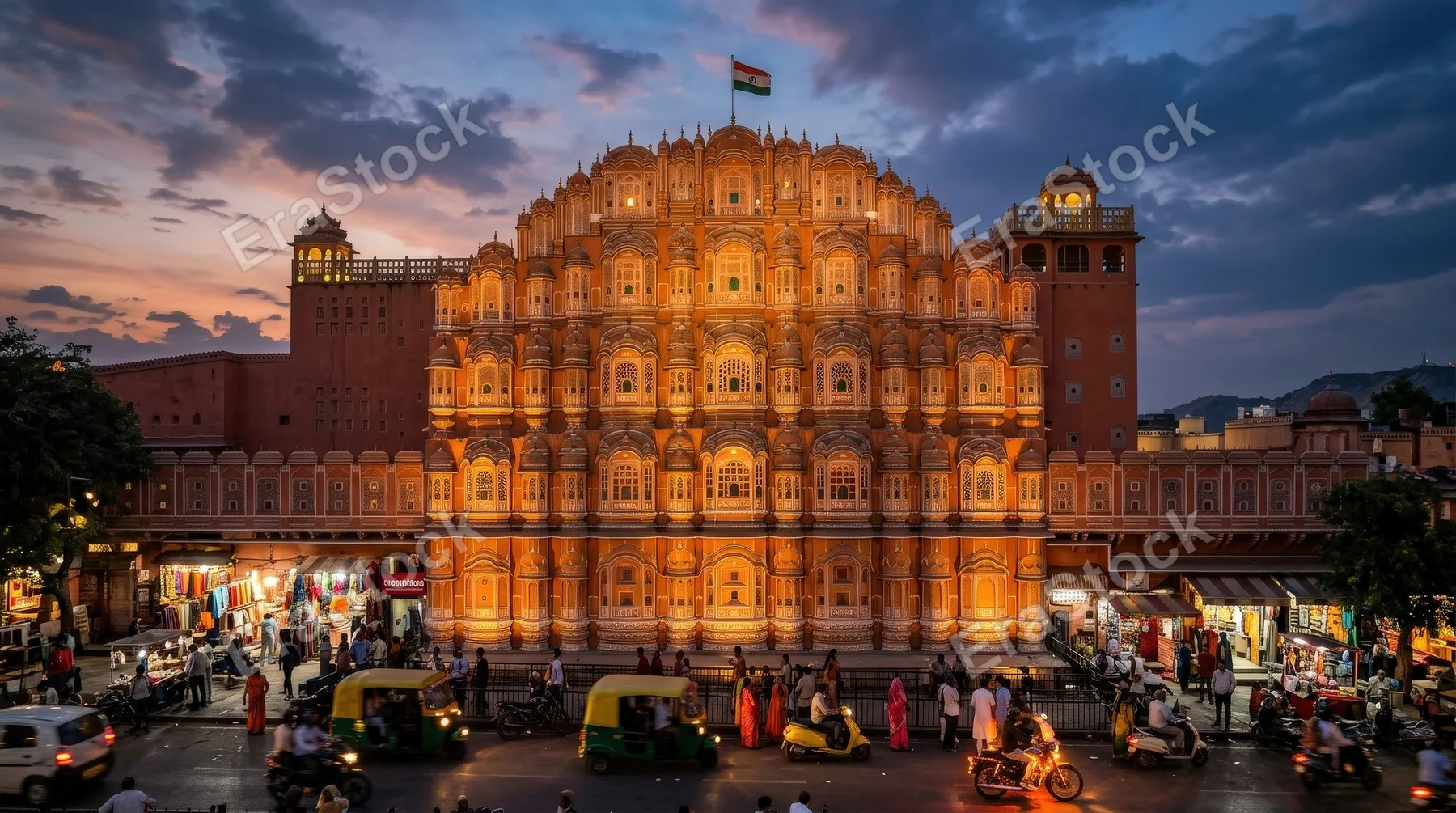 Hawa Mahal in Jaipur at dusk, intricate pink sandstone facade glowing under twilight skies, lively street below, warm architectural grandeur, atmospheric evening light, ultra-realistic, no logos.