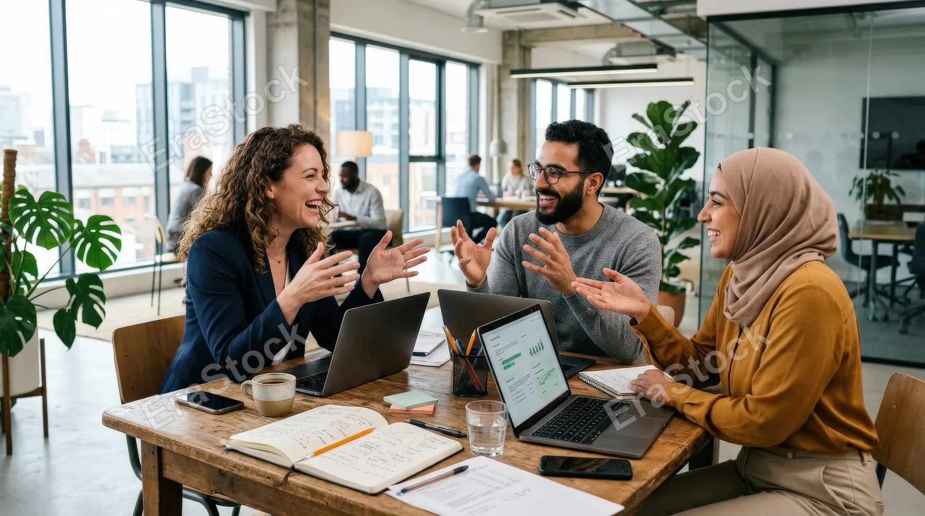 Three people having a lively discussion at a table in an office, expressive gestures, open laptops and notebooks, contemporary interior with natural daylight, energetic creative teamwork atmosphere,