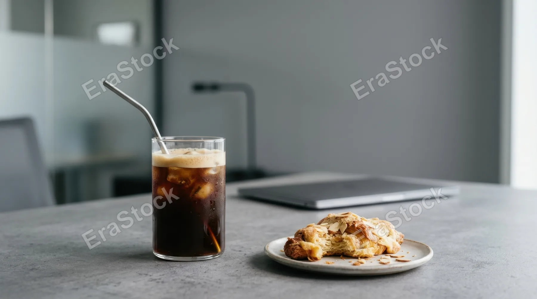 a graphic commercial composition featuring the glass of cold brew coffee against the soft gray backdrop of the corporate setting, with generous negative space for text