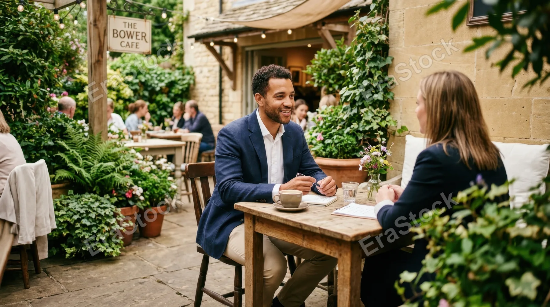 a wide shot captures a cozy cafe corner with a rustic wooden table set outdoors, showcasing a 32-year-old mixed-race male consultant engaged in a quiet meeting. the scene