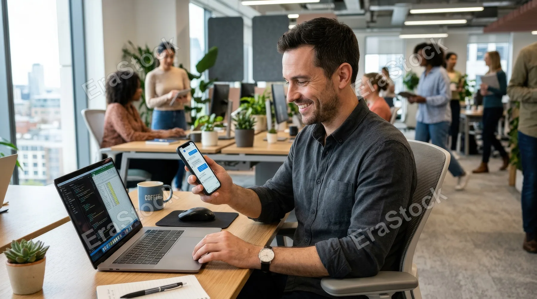 A smiling man using his smartphone while working on his laptop in an office, tidy desk, natural posture, modern workspace and an efficient upbeat atmosphere, ultra-realistic, no logos.