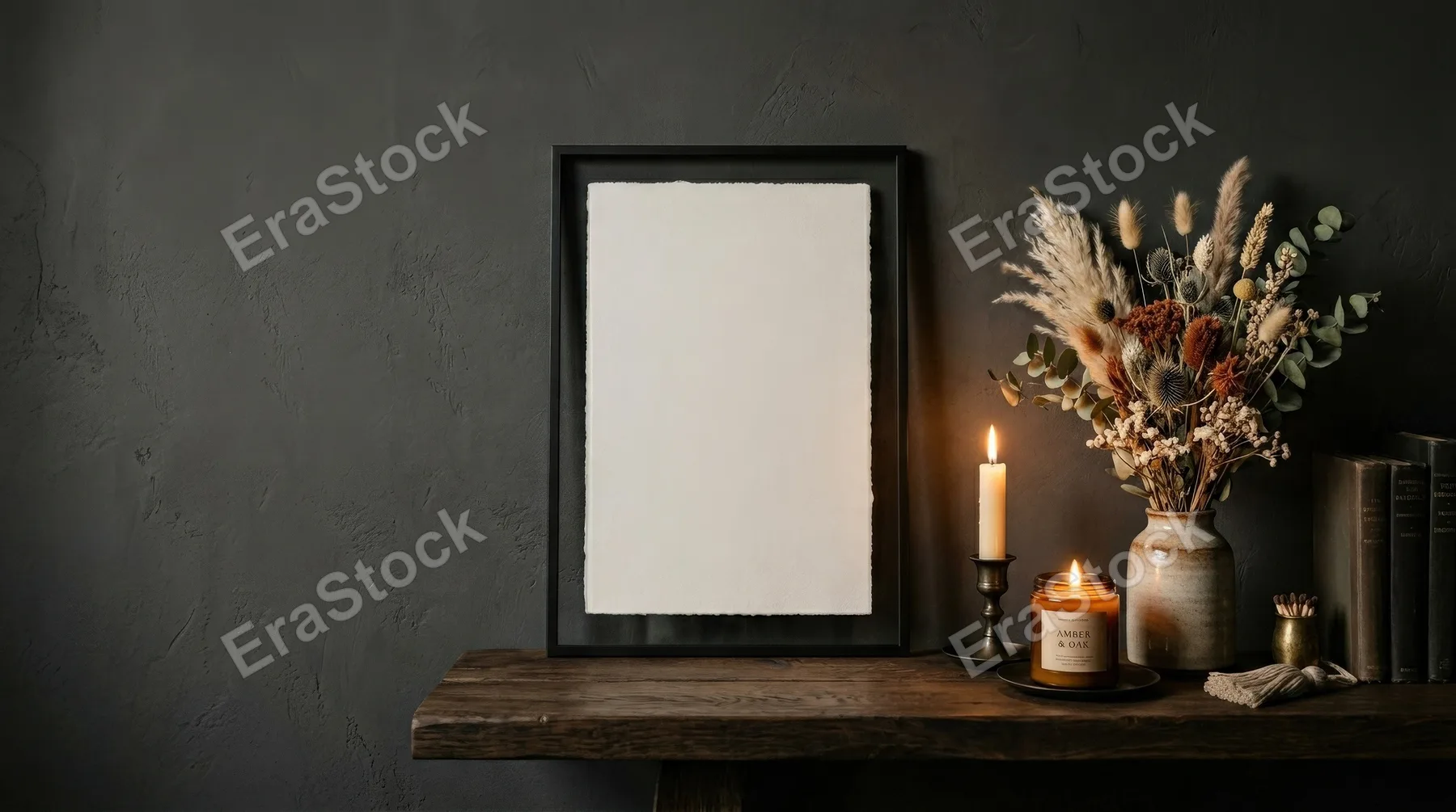 A blank poster frame on a shelf in a dark modern interior with dried flowers and candles, vertical format, moody luxury styling and soft warm glow, ultra-realistic, no logos.