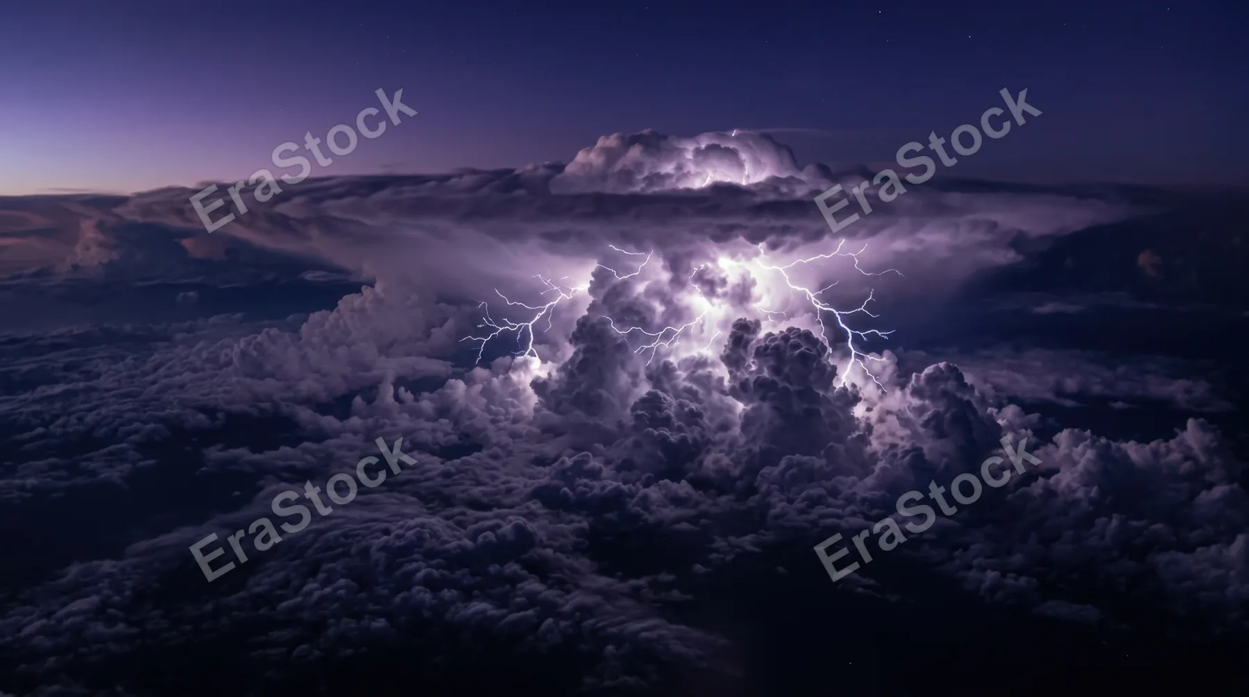 A thunderstorm cell viewed from above the clouds, the tops of cumulonimbus towers lit by lightning from within, electric veins branching across the cloud surface in