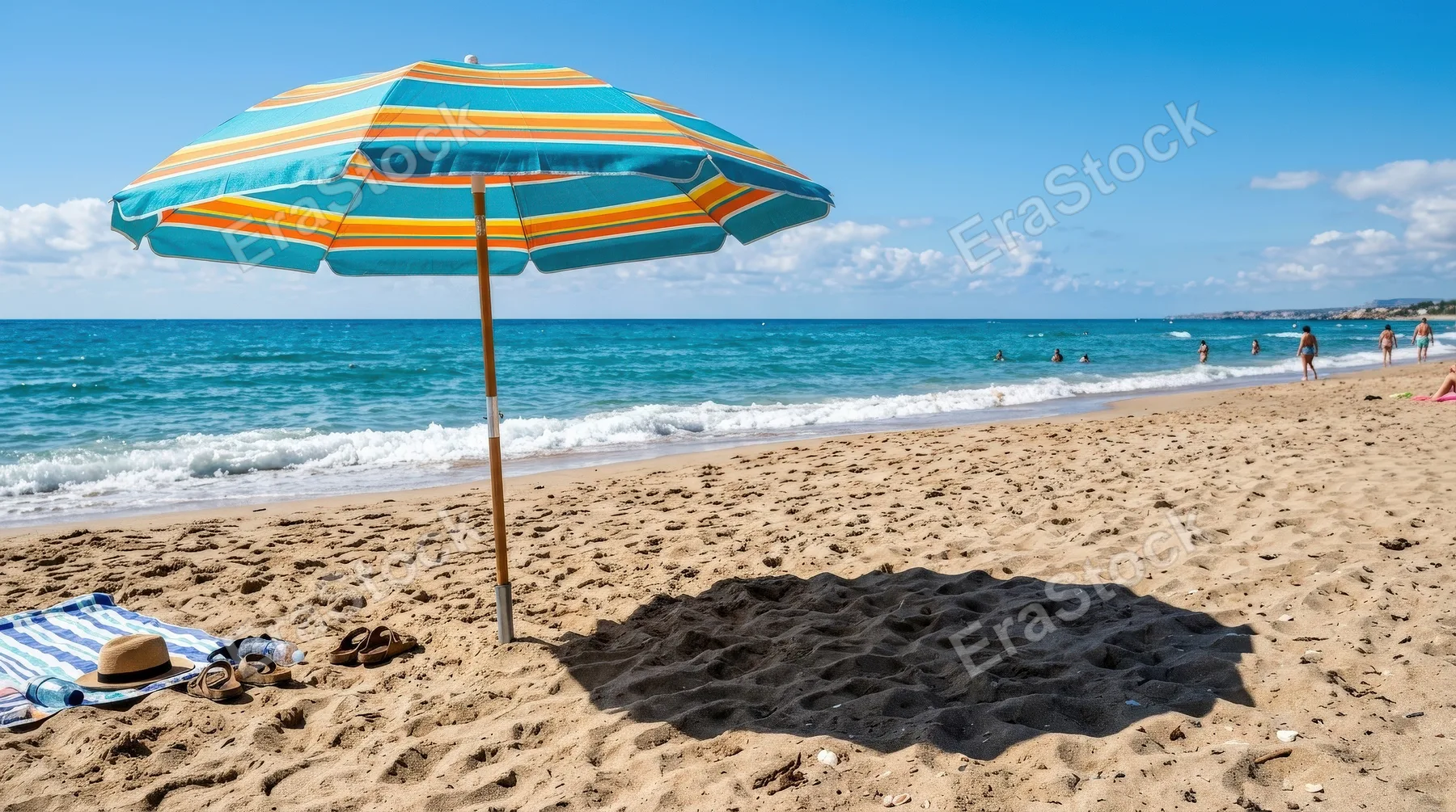 A colorful beach umbrella casting a sharp shadow on the sand with the ocean beyond, bright sunlight and vivid summer contrast, ultra-realistic, no logos.
