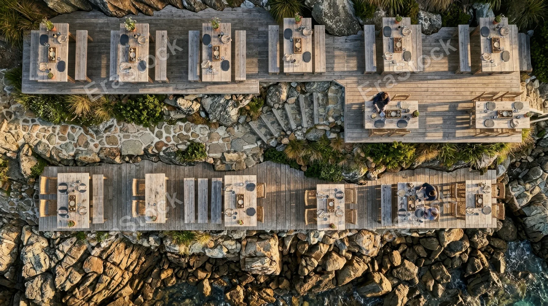 a distinct overhead angle featuring the terraced tables on the shore, crafted from natural materials and adorned with artisanal slate coasters and rustic wooden trays