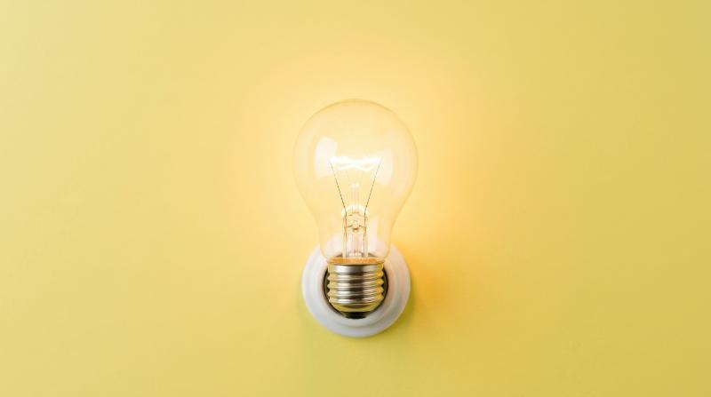 A white light bulb on a bright yellow background, pastel tones, clean minimal styling and radiant bright-idea symbolism, ultra-realistic, no logos.