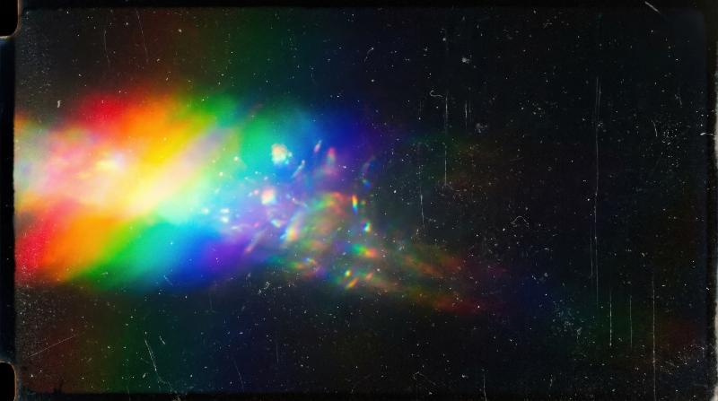 A rainbow light leak spreading across a black surface, delicate dust specks, worn film texture and luminous prism glow, dreamy vintage atmosphere, ultra-realistic, no logos.