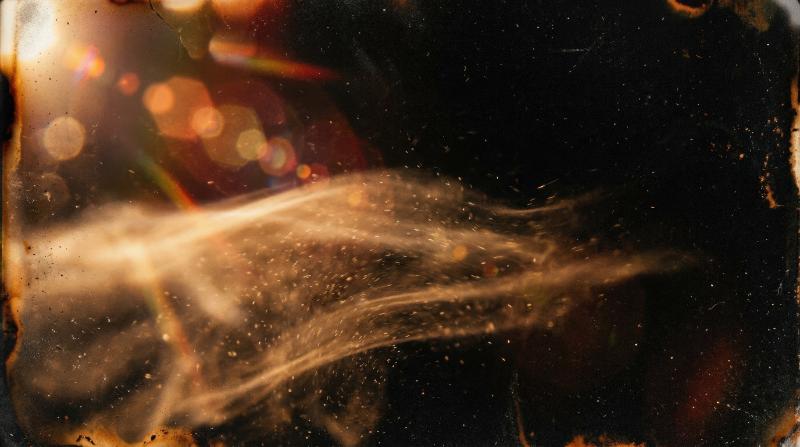 A warm dusty light leak with smoky motion blur and textured grain on black, analog lens flare and aged burn aesthetic, ultra-realistic, no logos.