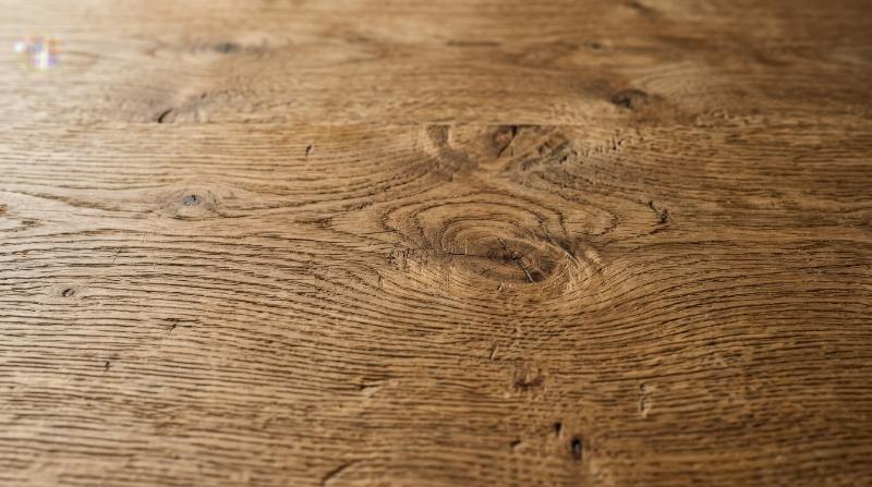 A natural wooden surface with visible grain, warm organic lines and subtle knots, timeless rustic texture background, ultra-realistic, no logos.