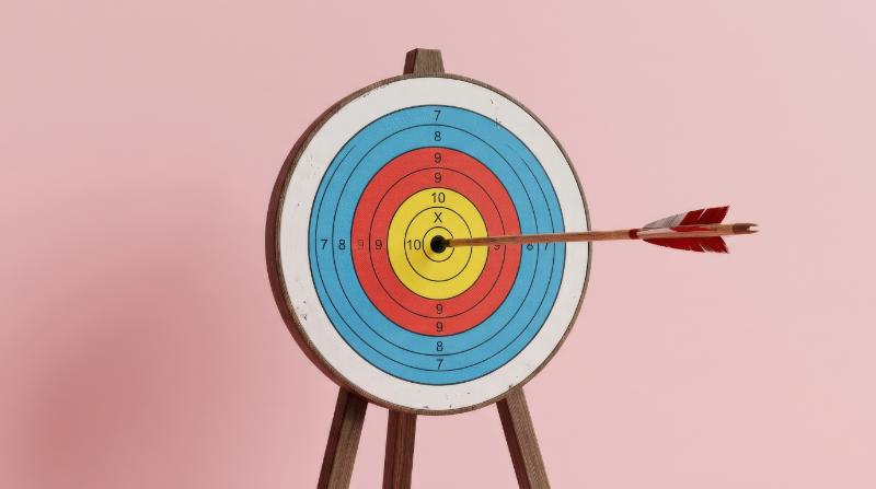 An arrow striking the exact center of a target on a pink pastel background, clean composition, success-focused energy, soft premium lighting, ultra-realistic, no logos.