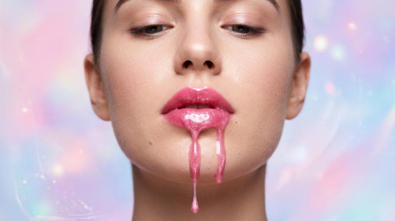 A beauty close-up of glossy pink lips dripping with luminous liquid against a pastel backdrop, smooth skin detail and modern surreal glamour, ultra-realistic, no logos.