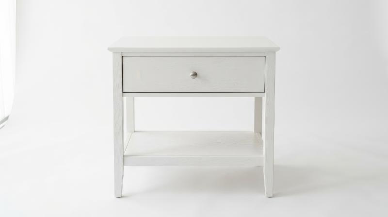 A white wooden nightstand with one drawer and a lower shelf on a plain white background, subtle wood texture and soft studio lighting, simple elegant atmosphere, ultra-realistic, no logos.