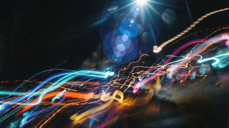 Abstract colorful motion-blurred light streaks on black, blue-toned lens flare and soft analog haze with vintage mood, ultra-realistic, no logos.