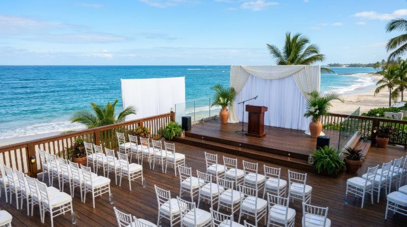 A beachfront stage with open ocean view prepared for presentations and events, clean elegant setup, bright sky and polished seaside sophistication, ultra-realistic, no logos.