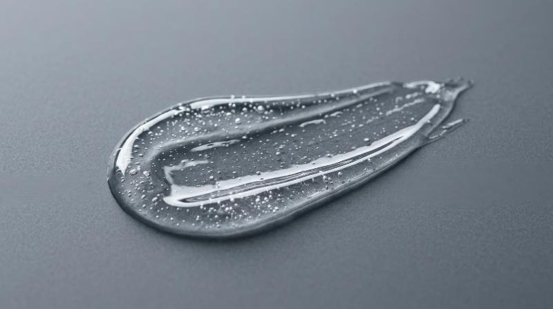 A clear skincare serum gel smear on a gray background, glossy translucent texture with tiny air bubbles, sleek cosmetic minimalism and clean scientific beauty mood, ultra-realistic, no logos.